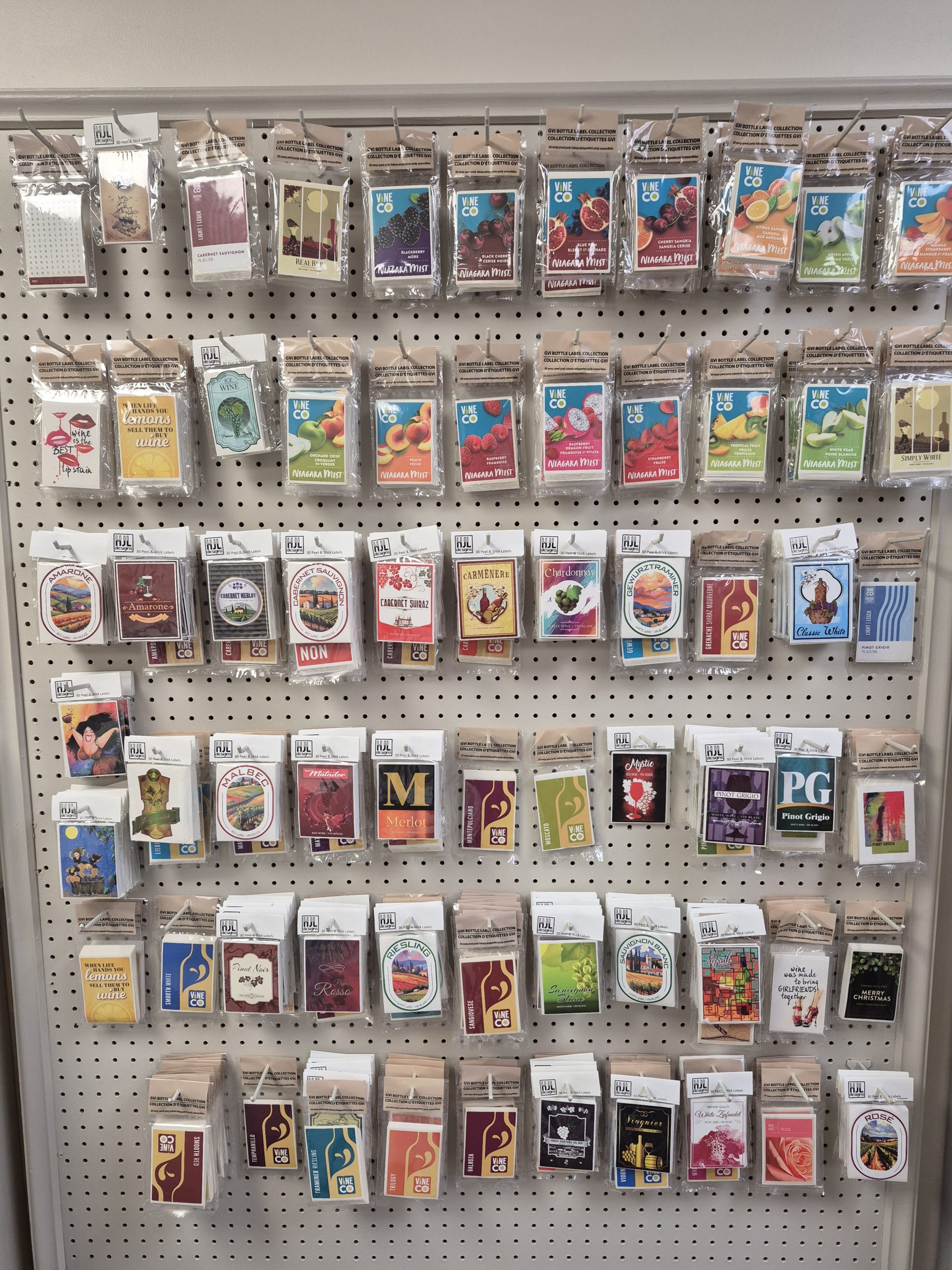 Assorted pre-made wine bottle labels in easy peel packs displayed on store wall